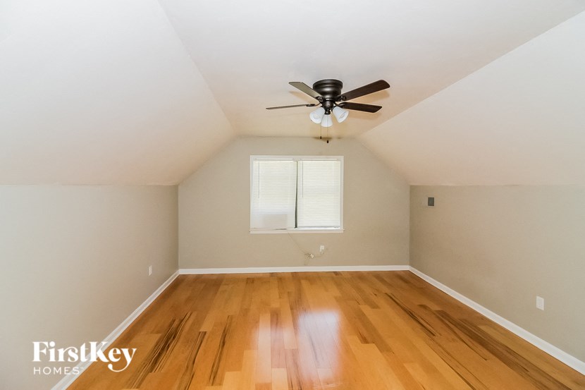 the upstairs bedroom with hardwood floors and a ceiling fan