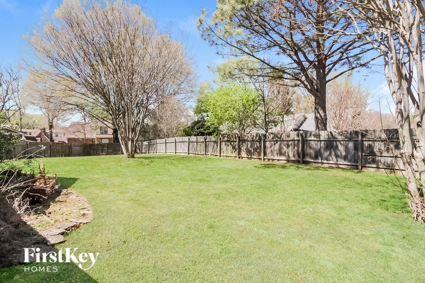 a fenced backyard with trees and a fence