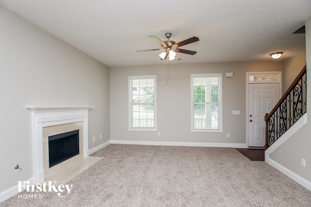 A spacious living room with a fireplace and a ceiling fan.