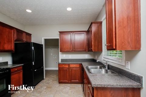 A kitchen with wooden cabinets and a black refrigerator.