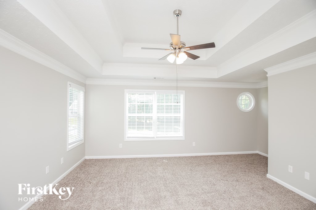 A spacious room with a ceiling fan and a window with blinds.