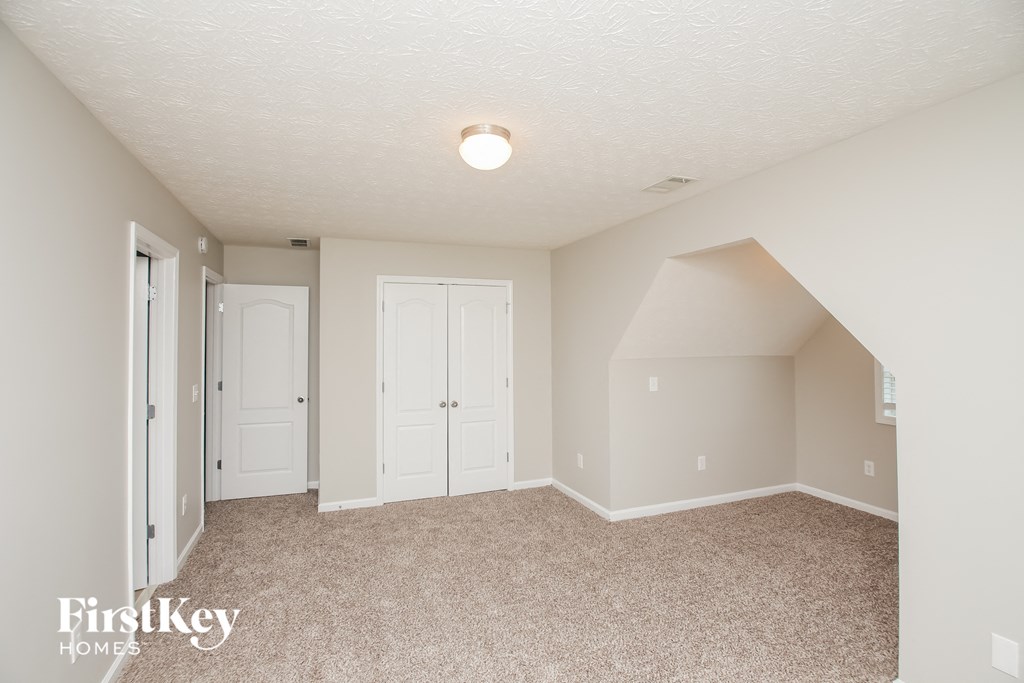 A bedroom with a carpeted floor and a ceiling light.