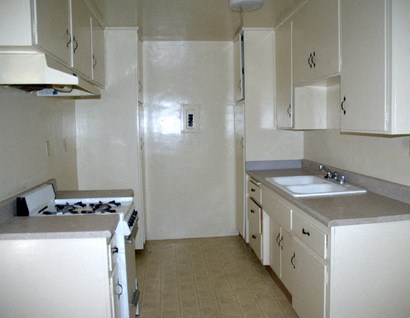 an empty kitchen with white cabinets and a sink