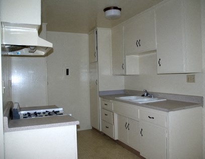 an empty kitchen with white cabinets and a sink