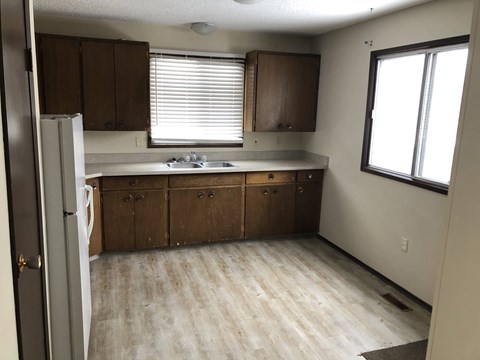 an empty kitchen with wooden floors and wooden cabinets