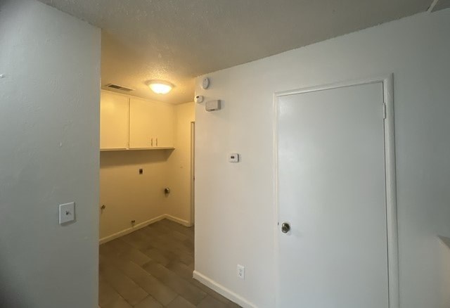 an empty room with a white door and a kitchen