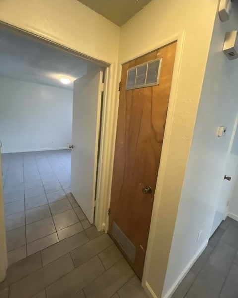 a hallway with a wooden door and a tile floor