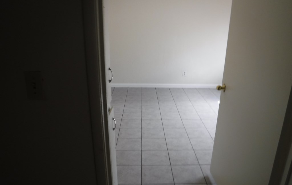 an empty room with a tiled floor and a white wall