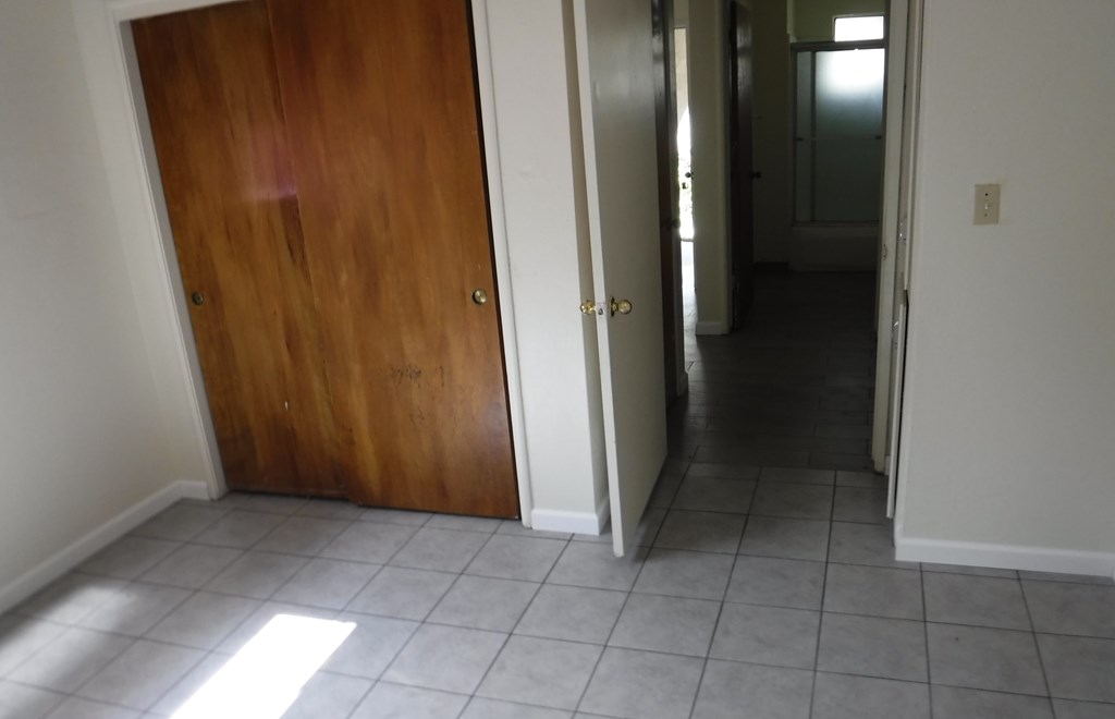 a hallway with a wooden door and a tiled floor