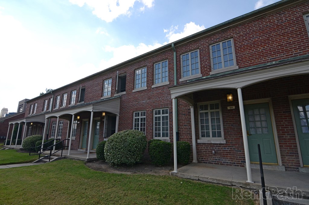 the front of a brick building with a porch and a green lawn