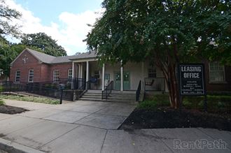 a building with a leasing office and a tree in front of it