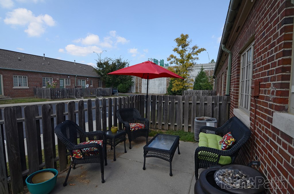 a backyard patio with chairs and a red umbrella