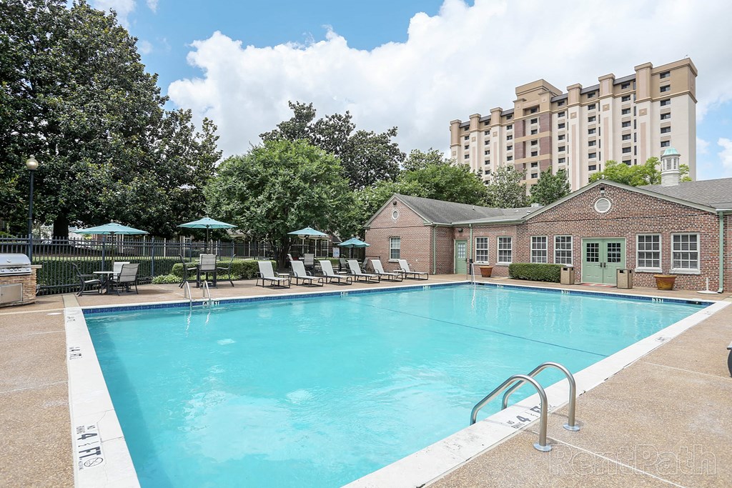 a swimming pool with chairs and a building in the background