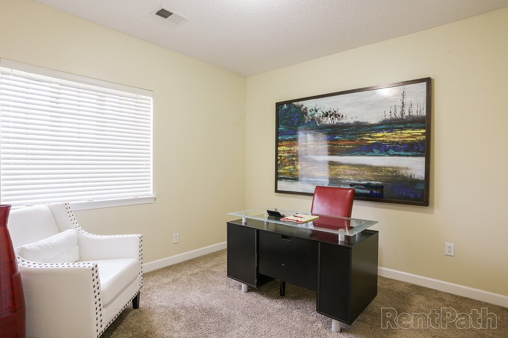 a home office with a desk and a painting on the wall