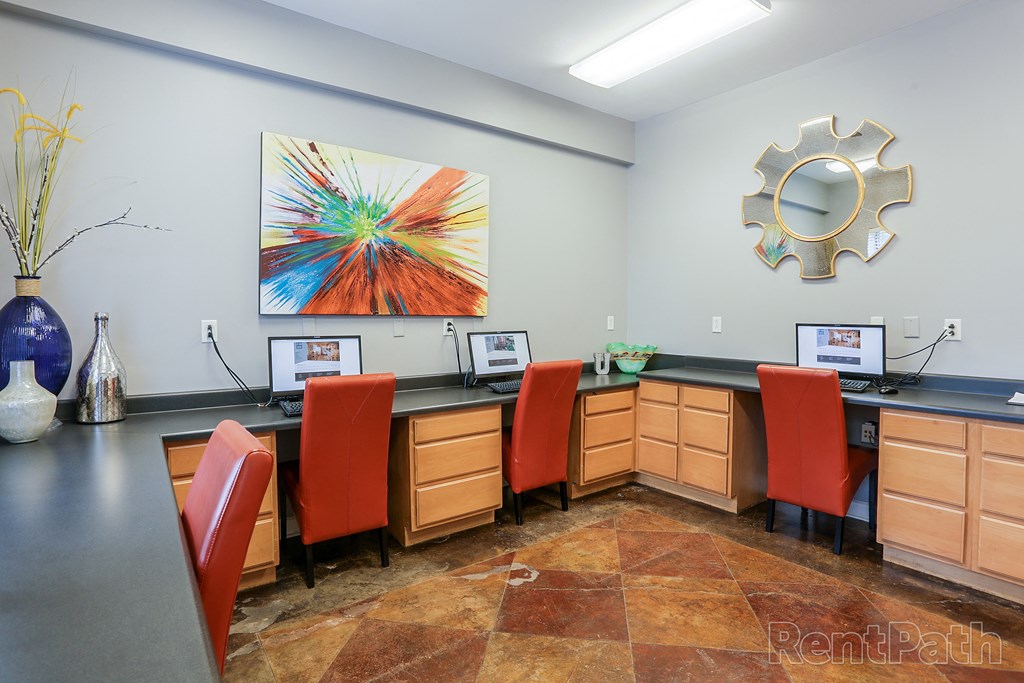 an office with desks and chairs and a painting on the wall