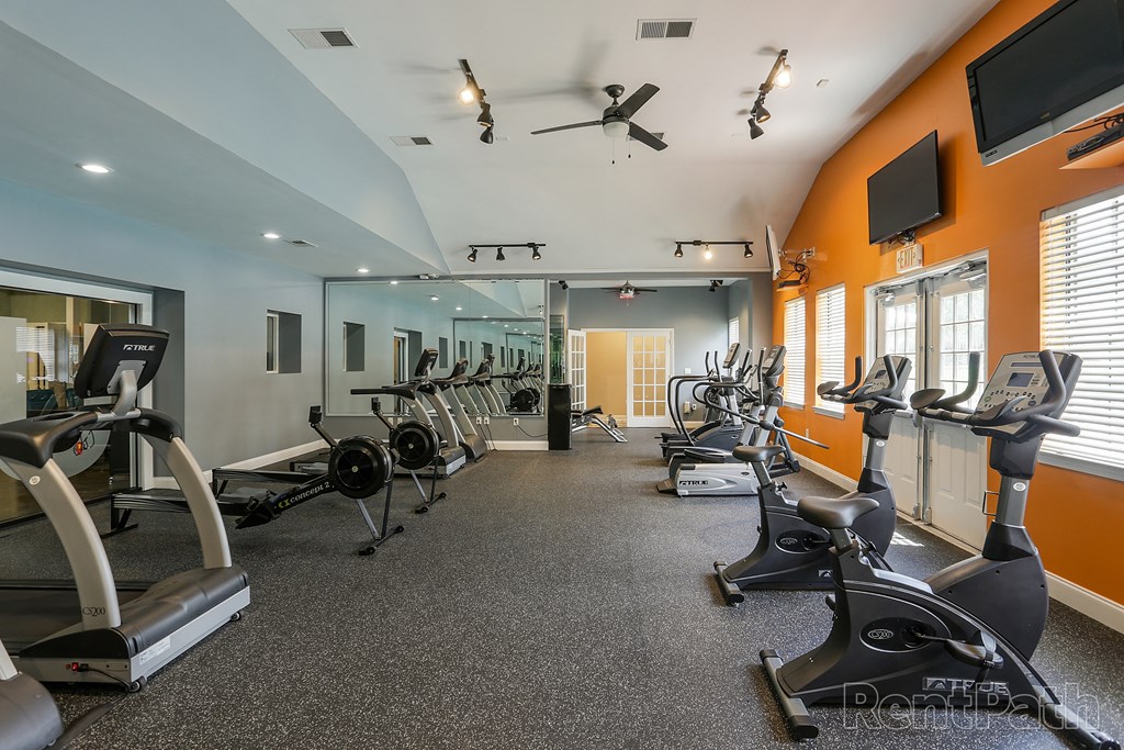 a gym with cardio equipment and weights on a carpeted floor