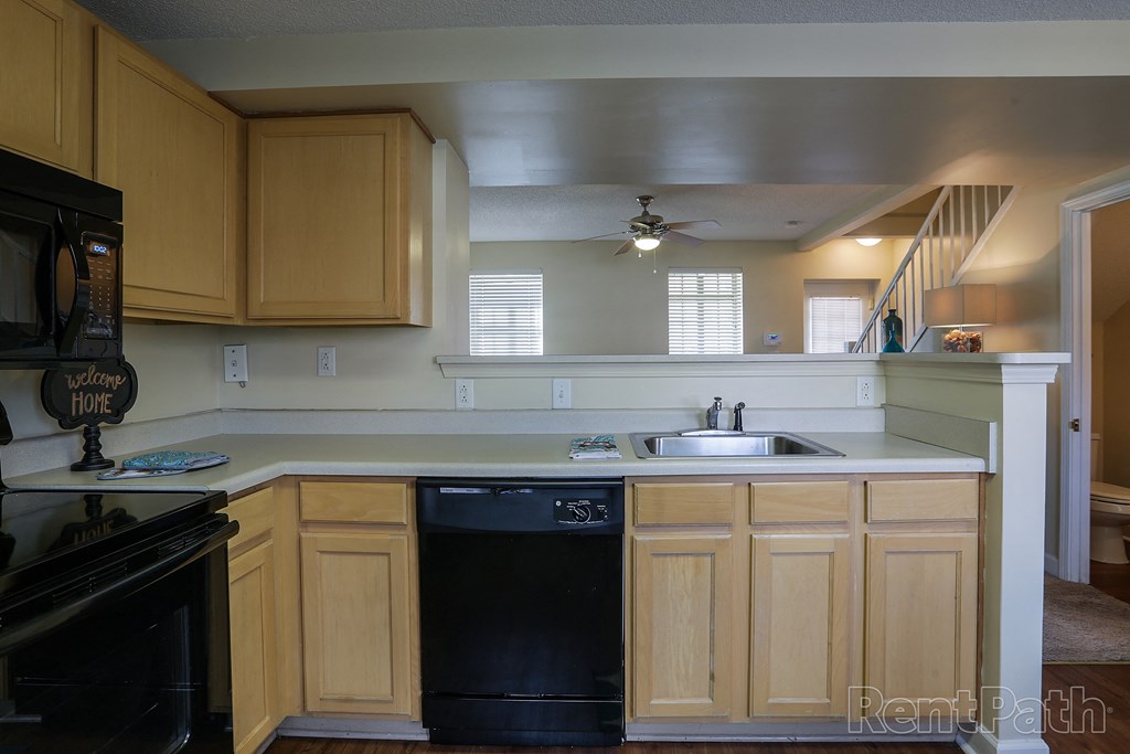 a kitchen with wooden cabinets and a black dishwasher