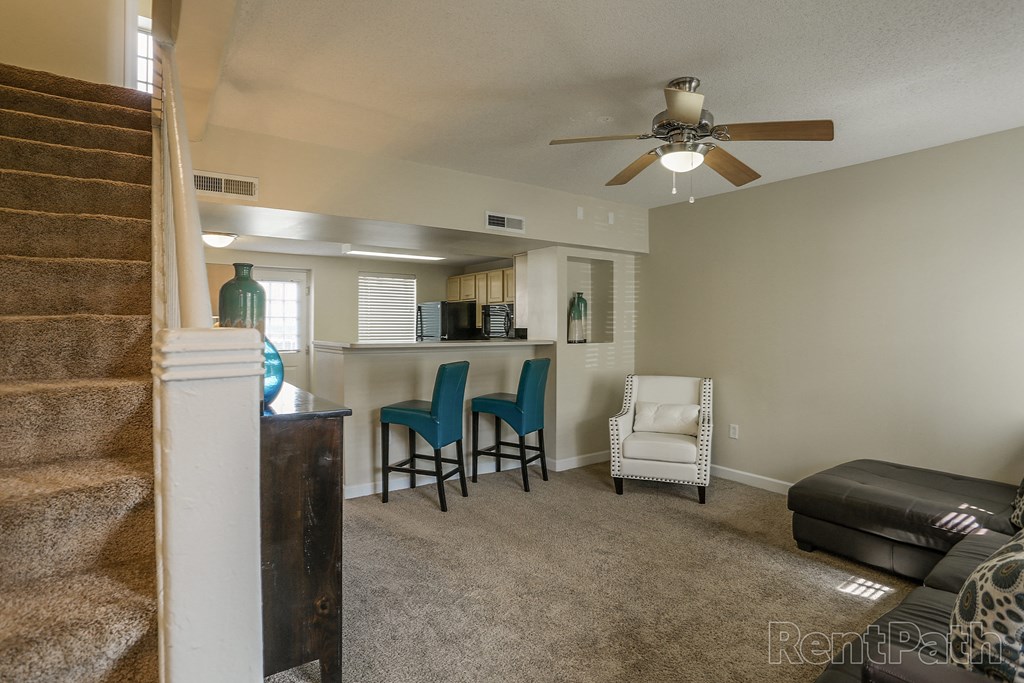 a living room with a kitchen and a ceiling fan