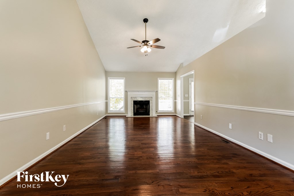 A spacious room with wooden floors and a ceiling fan.