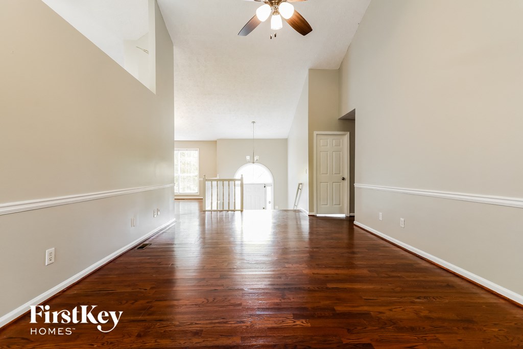 A spacious room with wooden floors and a ceiling fan.