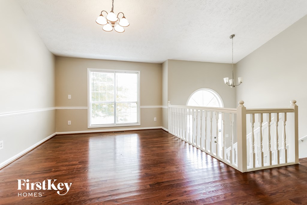 A spacious room with wooden floors and a white railing on the balcony.