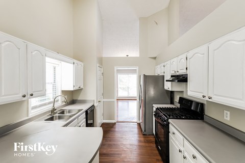 A kitchen with white cabinets and a stove top oven.