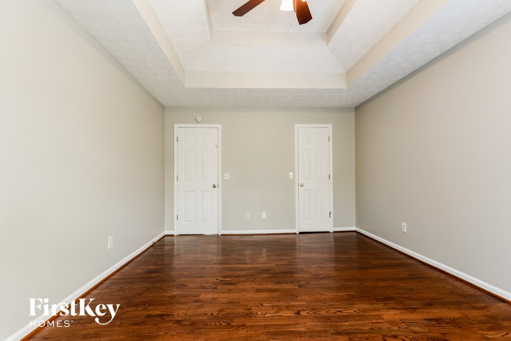 A room with wooden floors and two white doors.