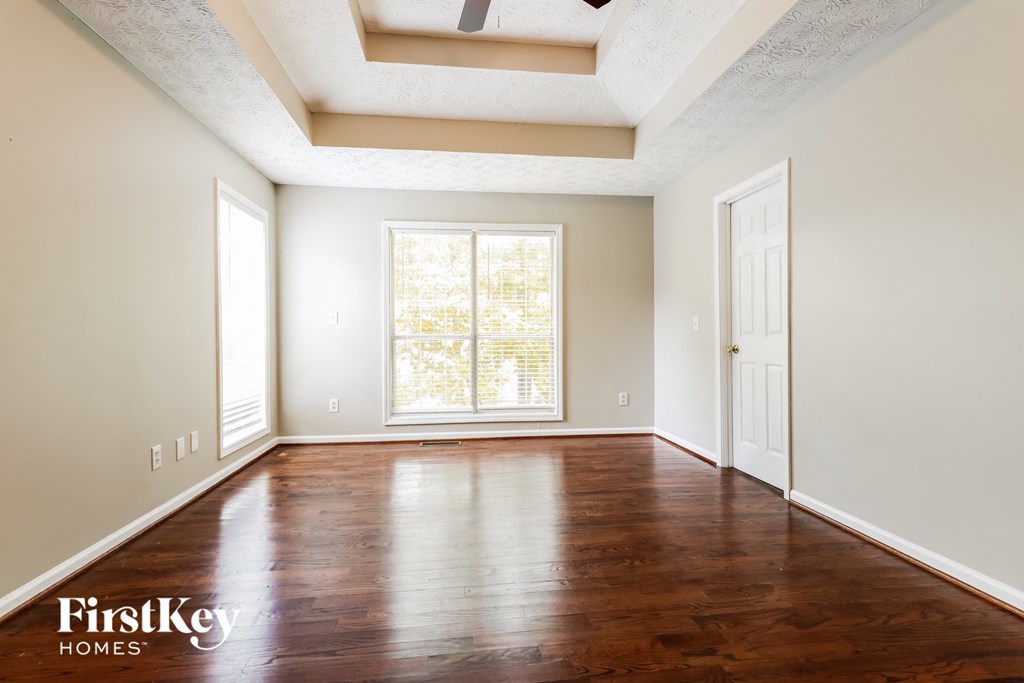 A room with wooden floors and a window with blinds.