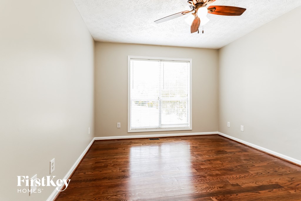 A room with a ceiling fan and wooden flooring.