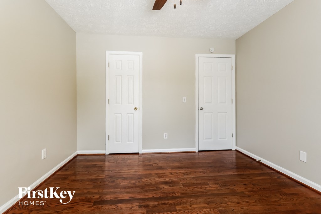 A room with two white doors and wooden floors.
