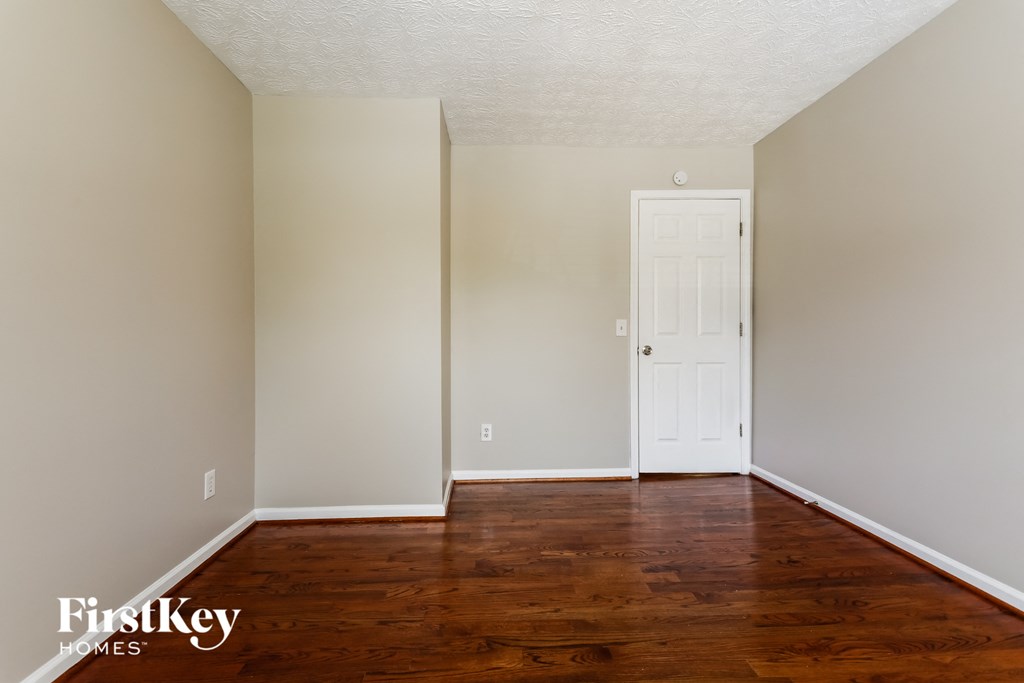 A room with a white door and wooden floors.