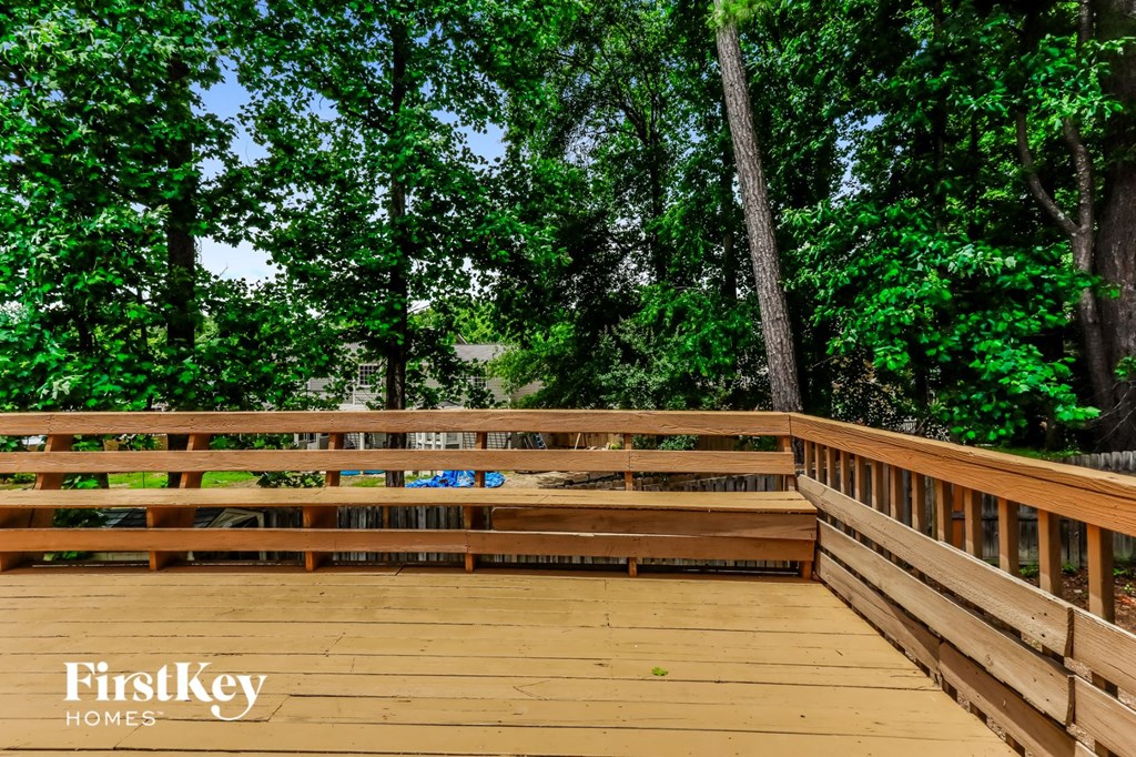 A wooden deck with a railing and trees in the background.