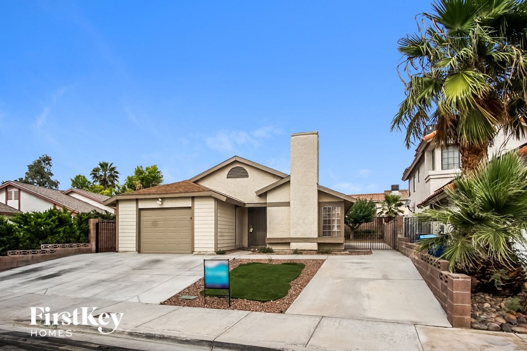 A house with a driveway and palm trees in front.
