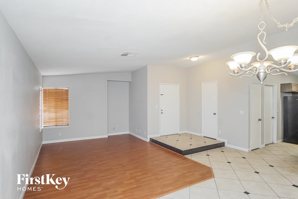 A large empty room with wooden floors and a chandelier.