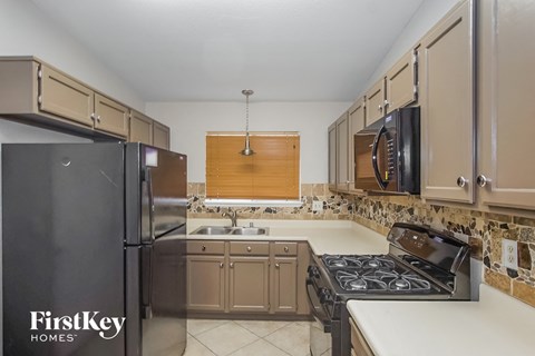 A kitchen with a black refrigerator and a stove top oven.