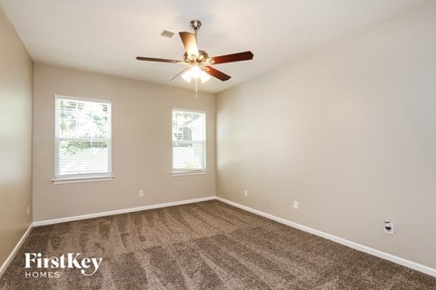 the living room is spacious and has carpet and a ceiling fan