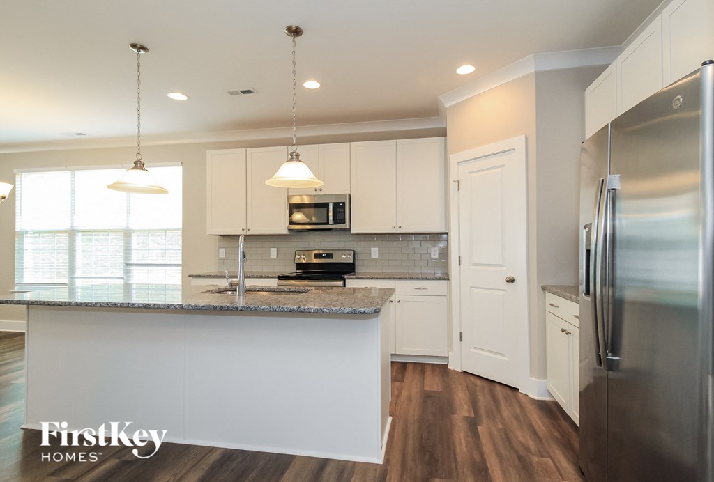 a white kitchen with stainless steel appliances and a granite counter top