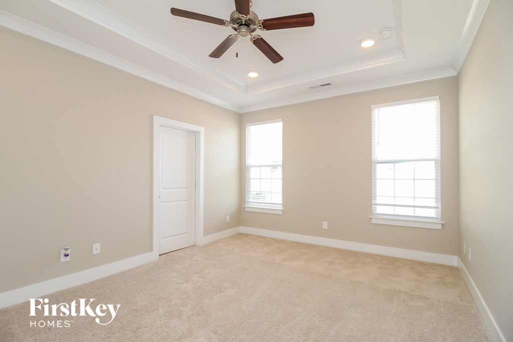 an empty living room with a ceiling fan and two windows