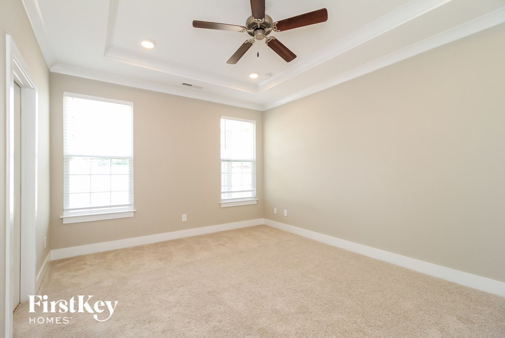 an empty living room with a ceiling fan and two windows