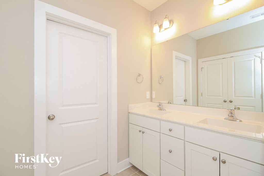 a white bathroom with two sinks and a mirror