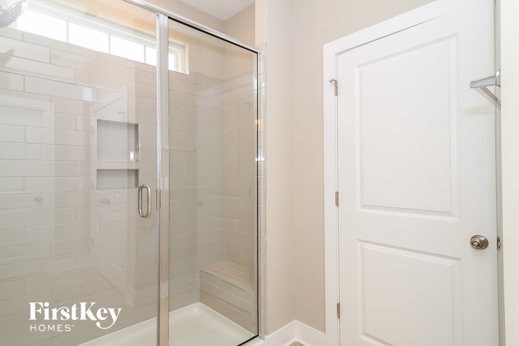 a bathroom with a shower and a white door