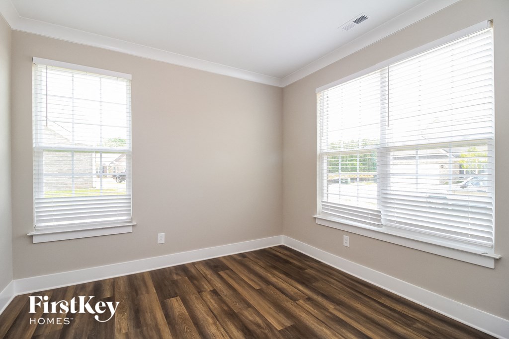 the living room of a home with wood floors and two windows