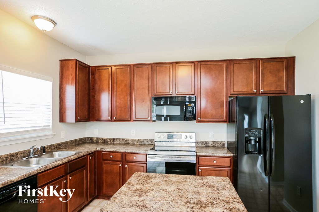 a kitchen with wood cabinets and black appliances and granite counter tops
