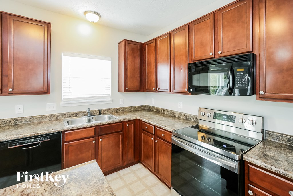 a kitchen with wood cabinets and black appliances and granite counter tops