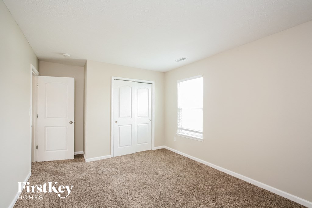 a bedroom with carpet and two doors and a window