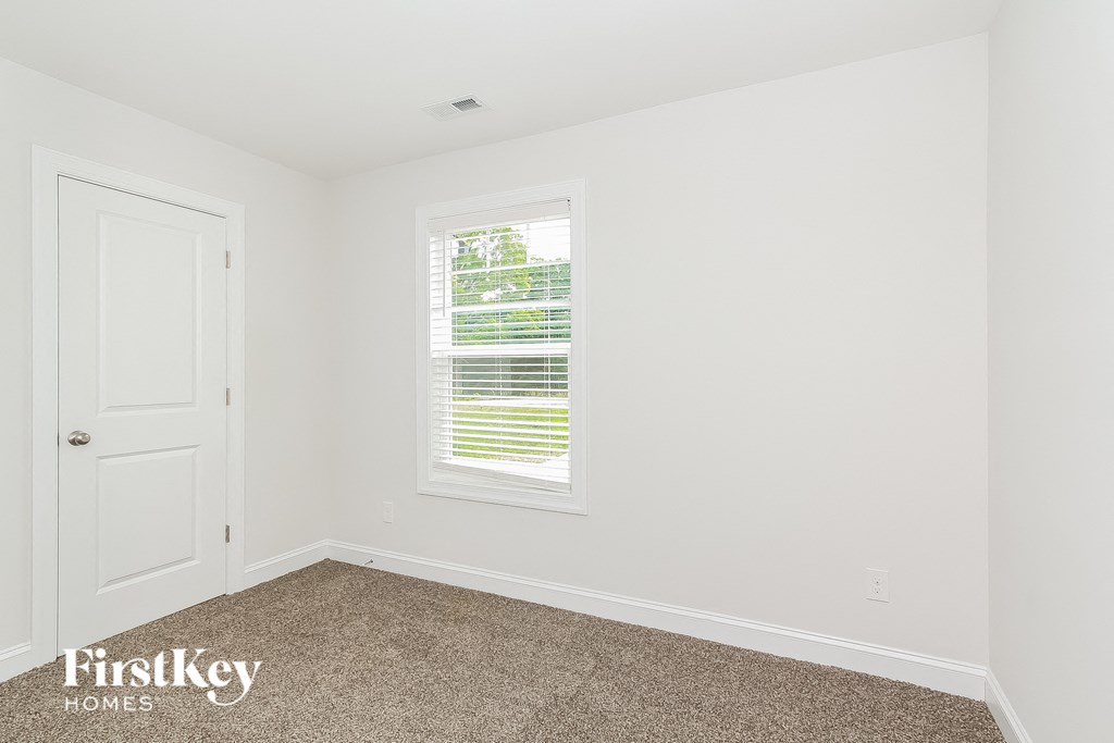 a bedroom with white walls and a white door and a window