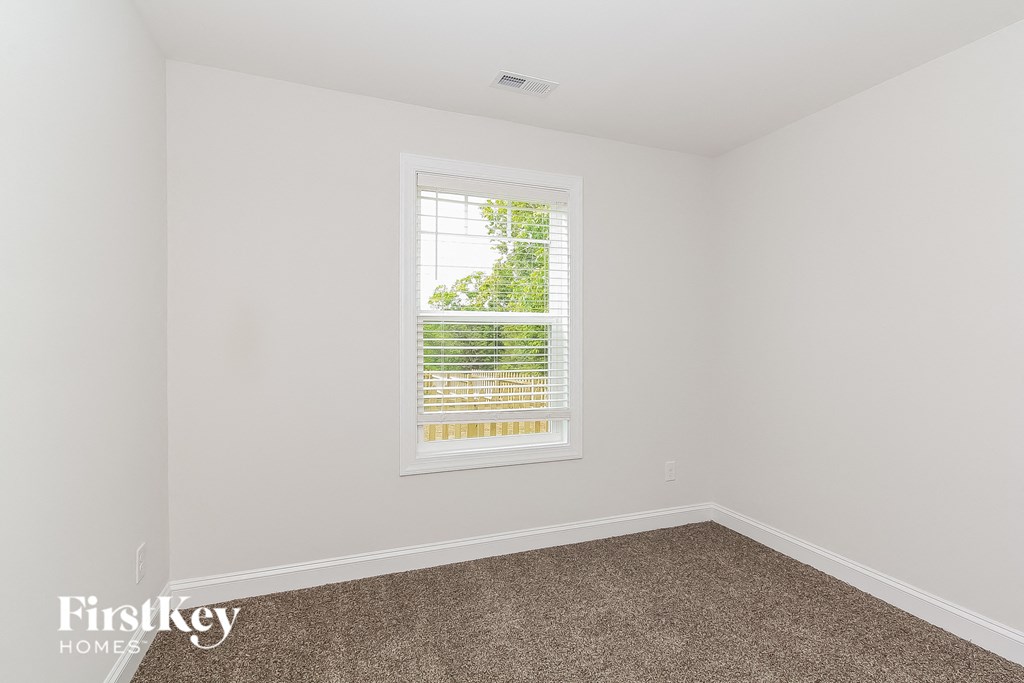 a bedroom with white walls and a window with blinds