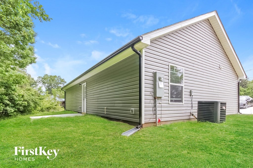 the side of a house with a garage and a grass yard