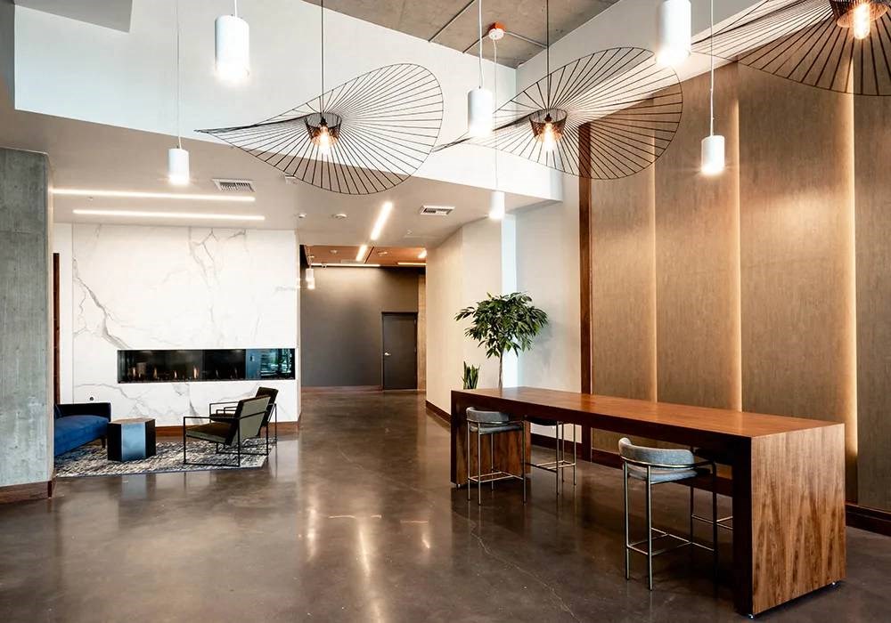 Lobby with large wooden table and seating for six. Polished concrete floor and marble fire place