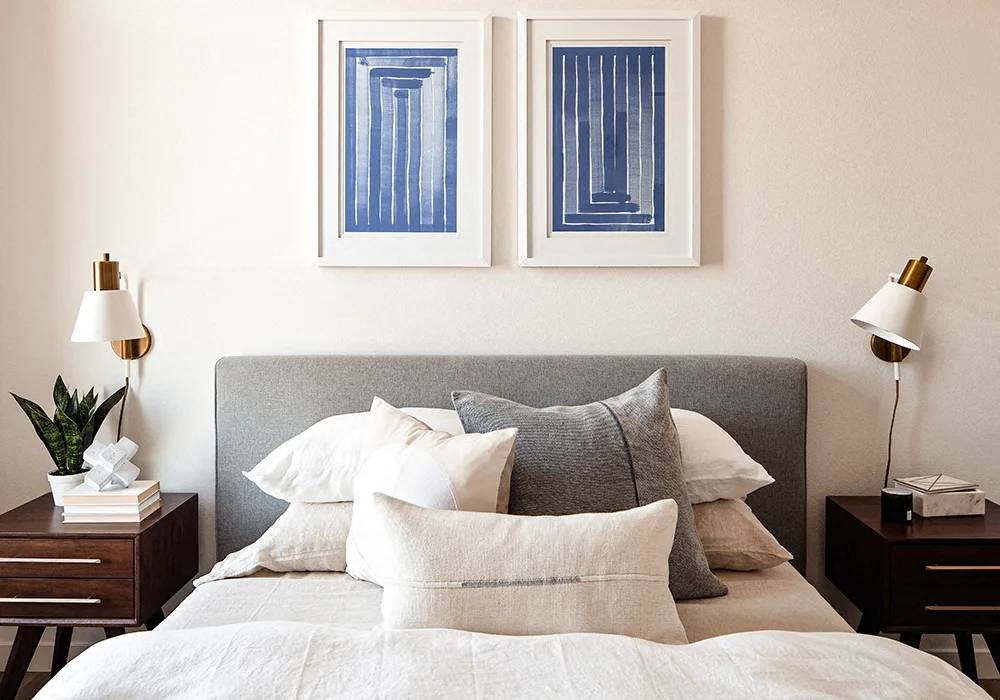 Queen bed with headboard, night stands, and pictures hung on wall